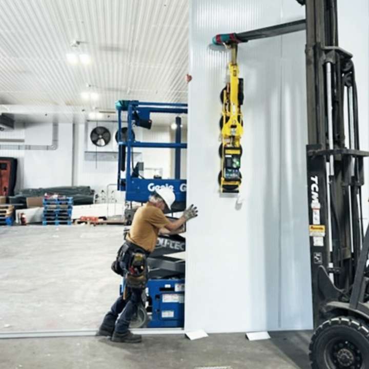 Travailleur positionnant un panneau isolant pour chambre froide à l'aide d’un chariot élévateur