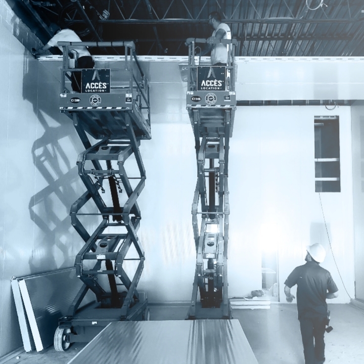 Travailleurs en nacelle installant le plafond dans une chambre froide en construction, en noir et blanc