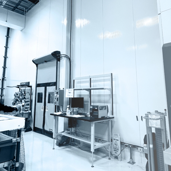 Poste de travail industriel avec ordinateur et porte de chambre froide dans un environnement manufacturier teinté de bleu