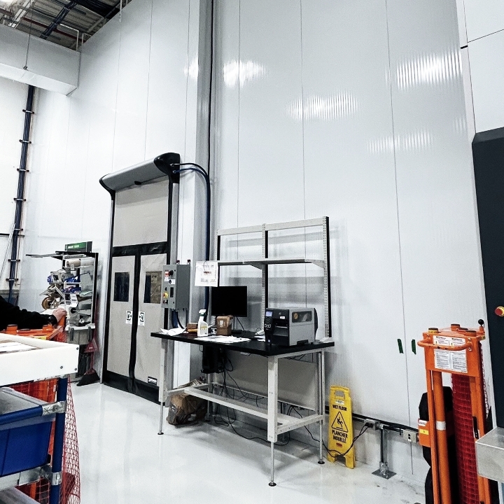 Poste de travail industriel avec ordinateur devant une porte de chambre froide en milieu manufacturier