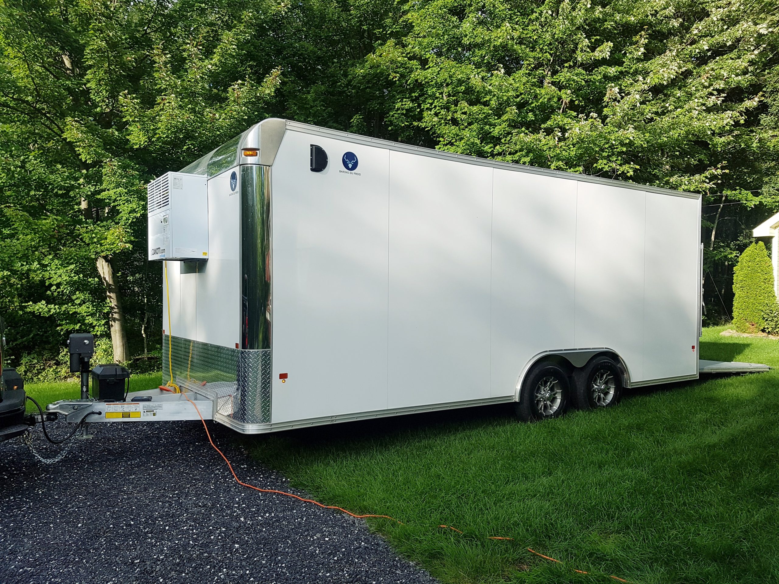 Remorque réfrigérée blanche à double essieu stationnée à l’extérieur sur une pelouse