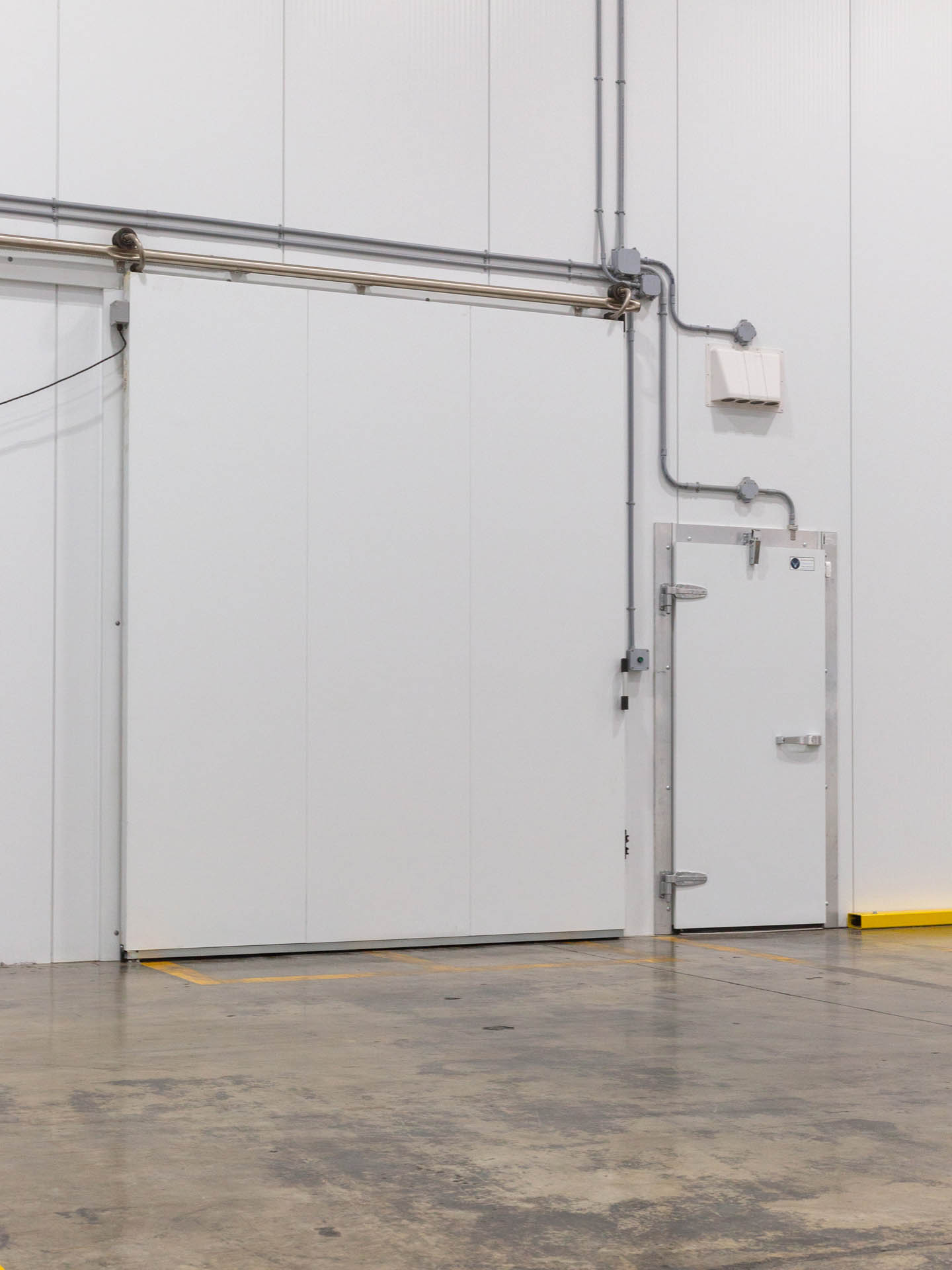 Grande porte coulissante et porte d'accès standard pour chambre froide dans un entrepôt industriel.